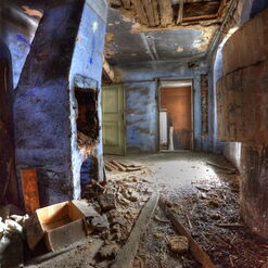 Verfallener Flur mit blauem Kamin und Schutt.